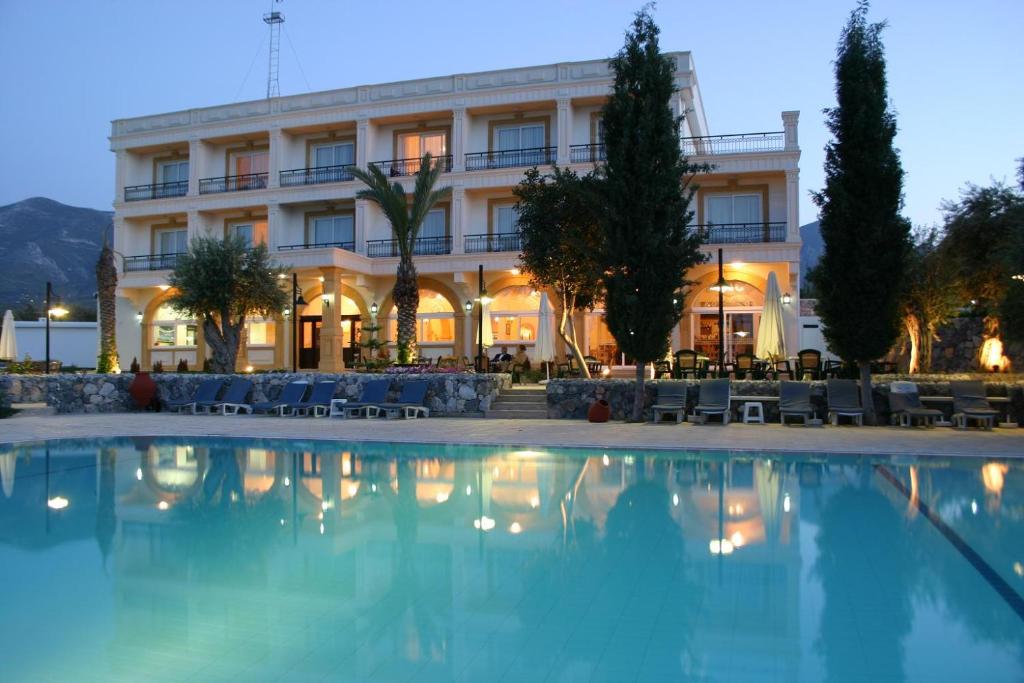 a hotel with a swimming pool in front of a building at Altinkaya Holiday Resort in Kyrenia