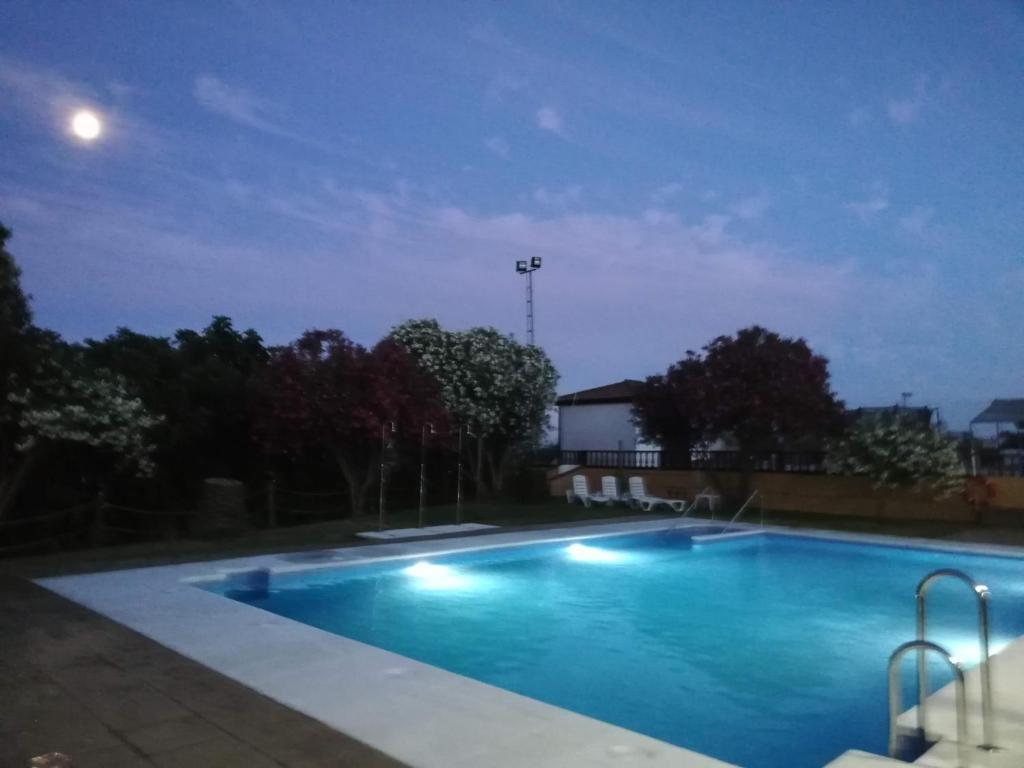 a swimming pool at night with the moon overhead at Hotel La Barca in Lepe