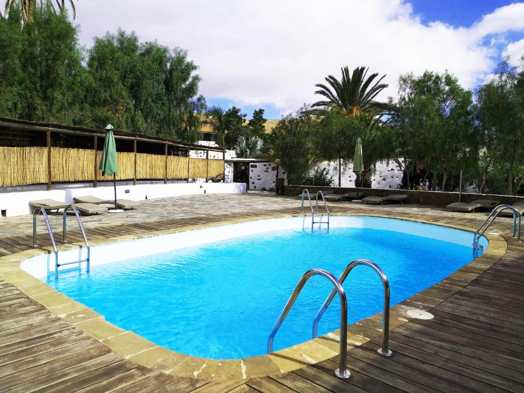 une piscine d'eau bleue et une terrasse en bois dans l'établissement Rural Rugama, à Puerto del Rosario
