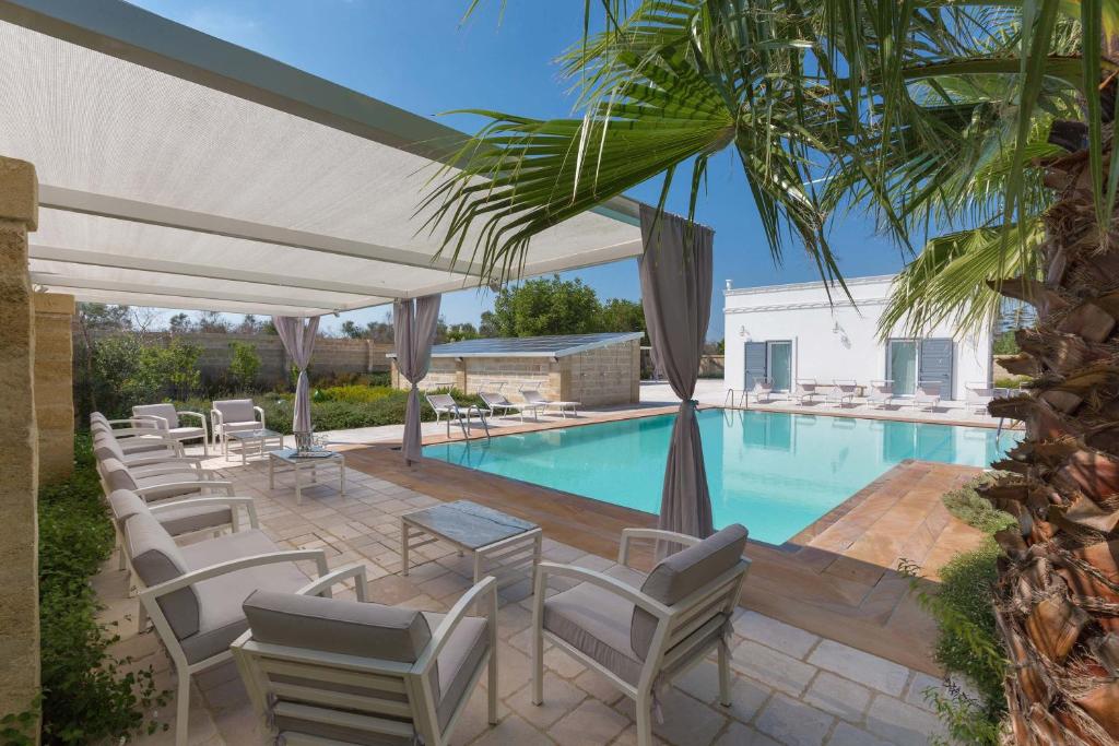 una piscina con un montón de sillas junto a una piscina en Villa Albarosa by Perle di Puglia, en Ruffano