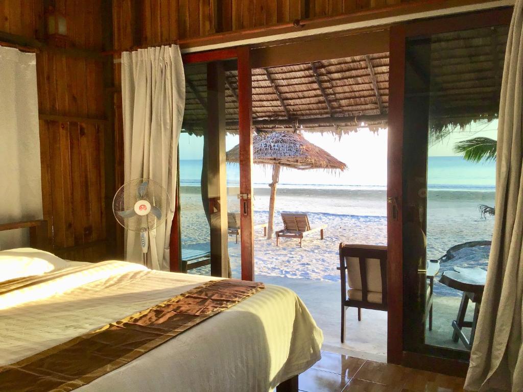 a bedroom with a bed and a view of the beach at Ailay in Ko Phayam
