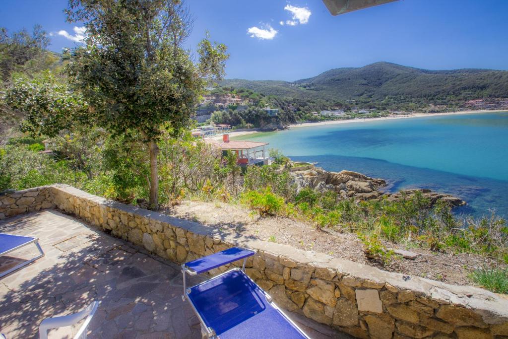 un paio di sedie blu sedute vicino a un muro di pietra di Un Nido sul Mare - Goelba a Portoferraio