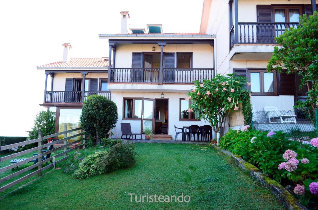 una casa grande con un patio delante en Chalet Las Calzadas - Jardín, parking y vistas increíbles, en San Vicente de la Barquera