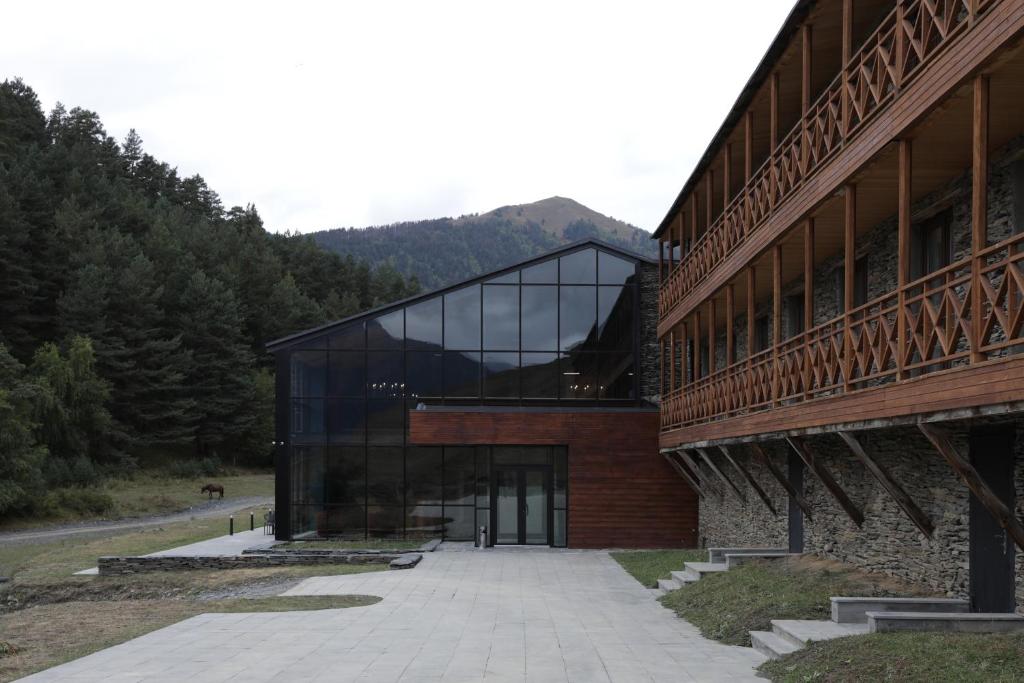 a large glass building with a mountain in the background at Hotel Samzeo in Omalo