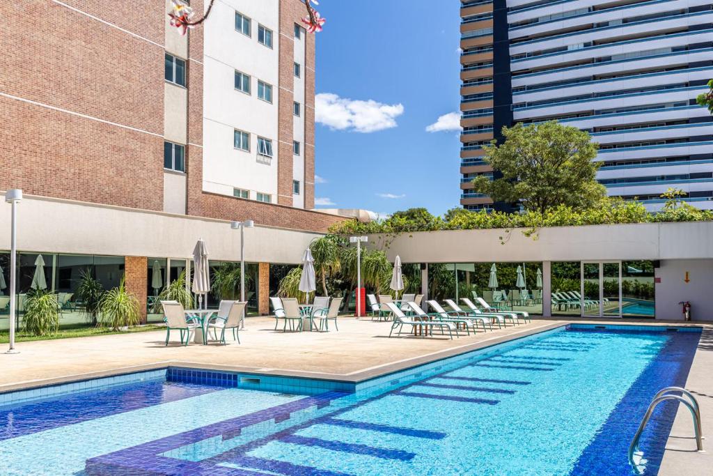 a swimming pool with chairs and a building at Iu-á Hotel in Juazeiro do Norte