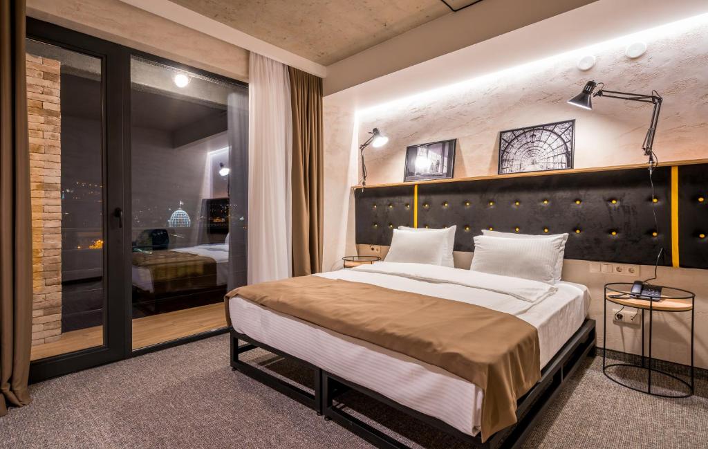 a bedroom with a large bed and a large window at Tbilisi Story Hotel in Tbilisi City