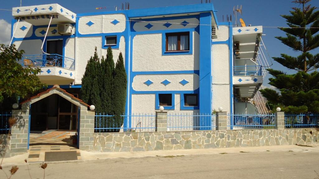 a blue and white building with a gate at Panorama Hotel in Ammoudia