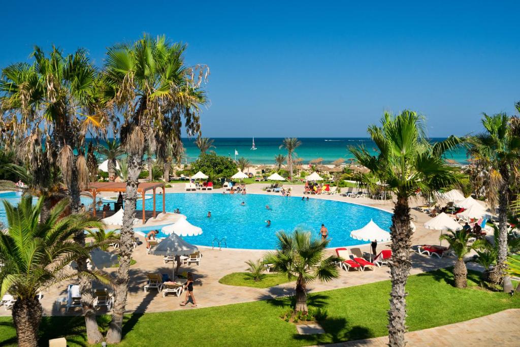 een uitzicht over het zwembad van het resort met palmbomen bij Iliade Aqua Park Djerba in Houmt Souk