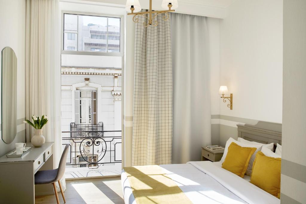 a bedroom with a bed and a desk and a window at Hotel Luxembourg in Thessaloniki