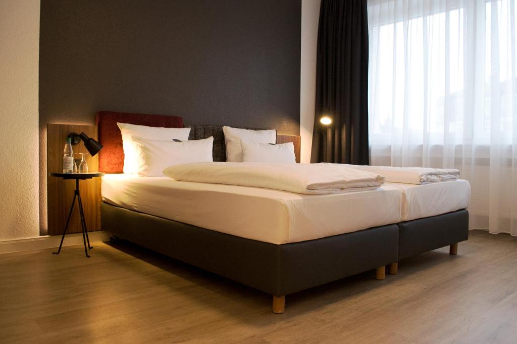 a bedroom with a bed with white sheets and a window at Hotel am Schlosstheater in Fulda