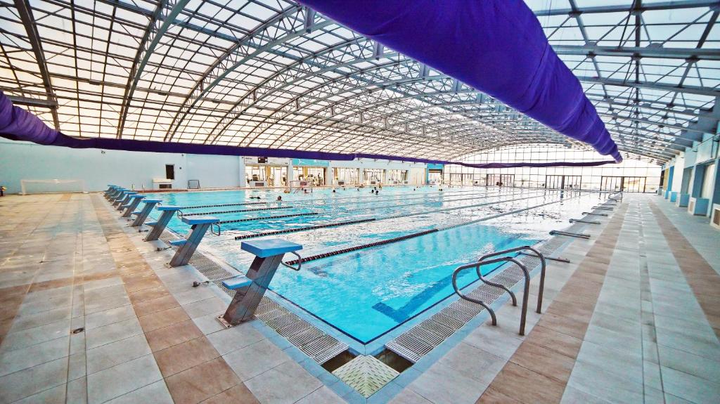 a large indoor swimming pool with many tables and chairs at Plaza Inn Batumi in Batumi