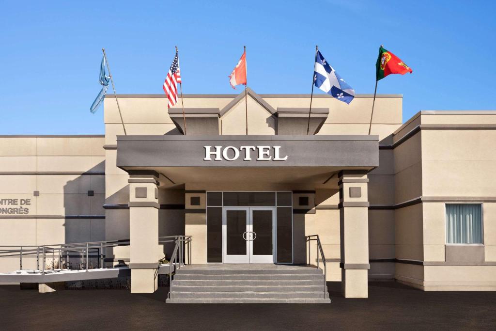 un hotel con banderas frente a un edificio en Hotel Days Inn Blainville & Centre de Conférence, en Blainville