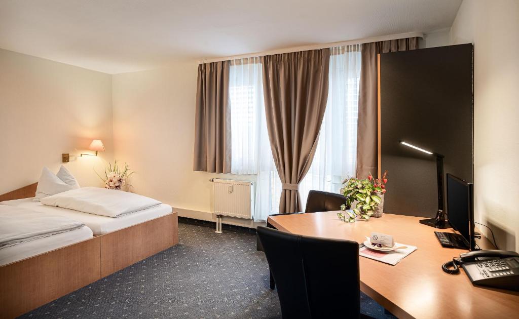 a hotel room with a bed and a desk at Sunibel Inn in Reinheim