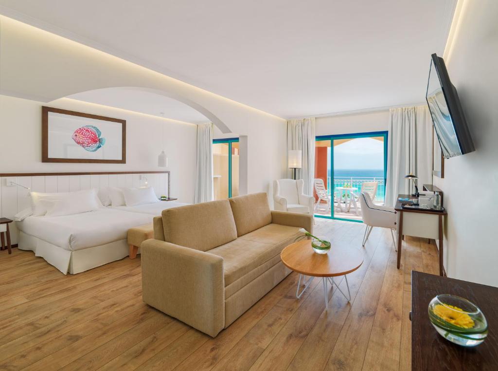 a hotel room with a bed and a couch and a table at H10 Playa Esmeralda - Adults Only in Costa Calma
