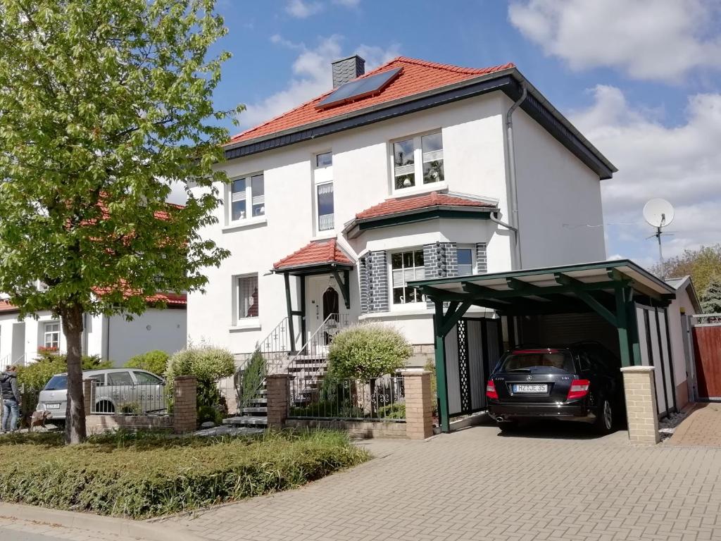 ein weißes Haus mit einem Auto in der Garage in der Unterkunft Ferienwohnung 40qm Gernrode in Gernrode - Harz