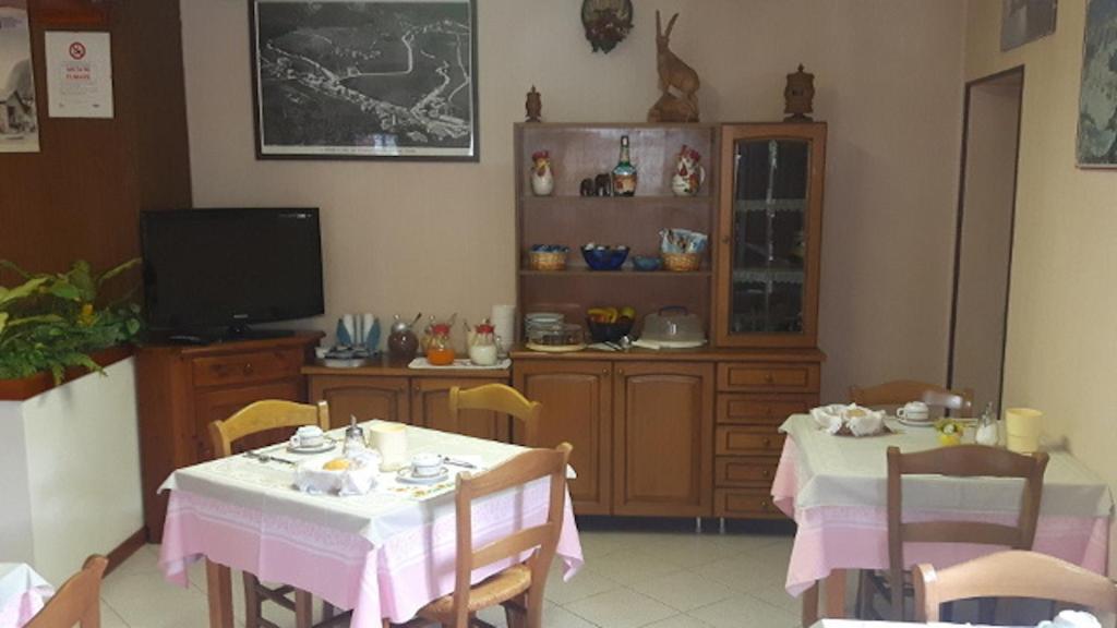 jadalnia z dwoma stołami i telewizorem w obiekcie Affittacamere Entreves w mieście La Thuile
