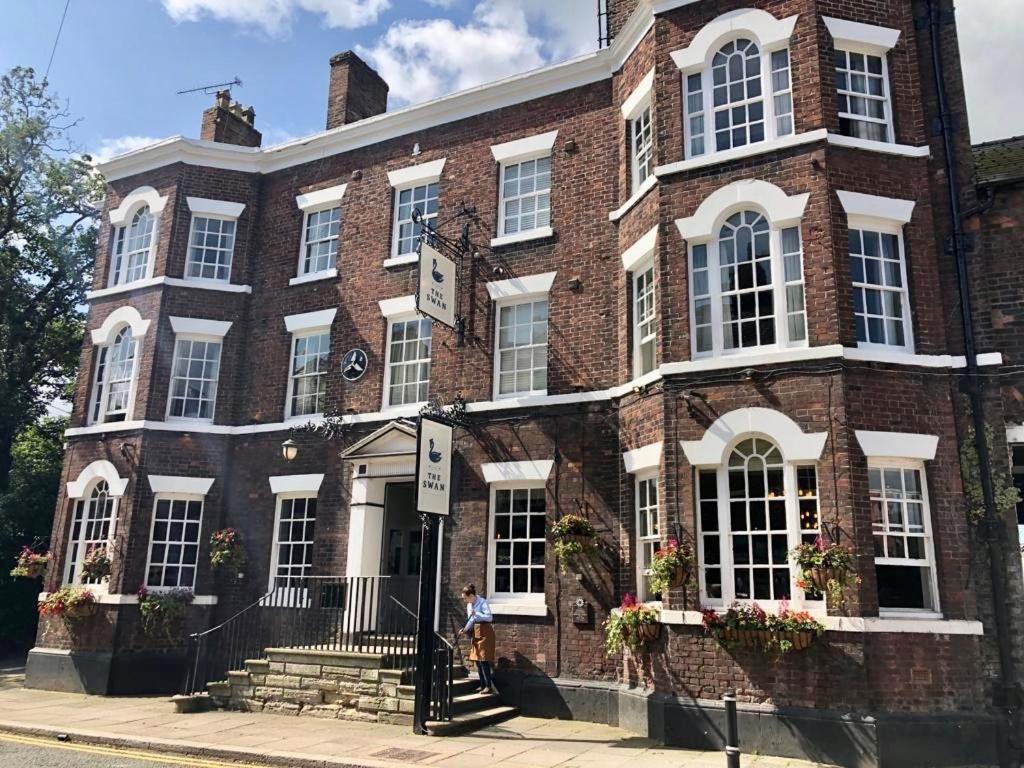 una persona caminando frente a un edificio de ladrillo en The Swan at Tarporley en Tarporley