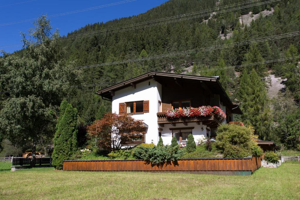 ein Haus mit Blumen vor einem Berg in der Unterkunft Landhaus Zauser in Sankt Anton am Arlberg