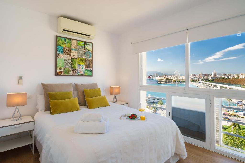 a bedroom with a white bed with a large window at LU&CIA Málaga Skyline in Málaga