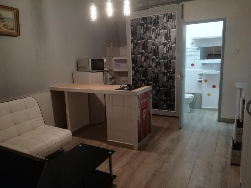 a living room with a table and a chair and a kitchen at STUDIO DU BAOU DE CADOLIVE in Cadolive