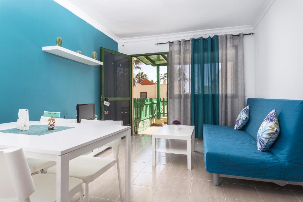 8202 - Wifi Costa Calma Bungalow في كوستا كالما: غرفة معيشة مع أريكة زرقاء وطاولة