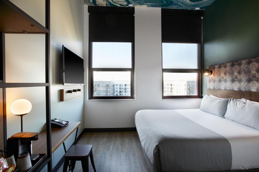 Una habitación de hotel con una cama y dos ventanas. en TRYP by Wyndham Pittsburgh&#47;Lawrenceville, en Pittsburgh