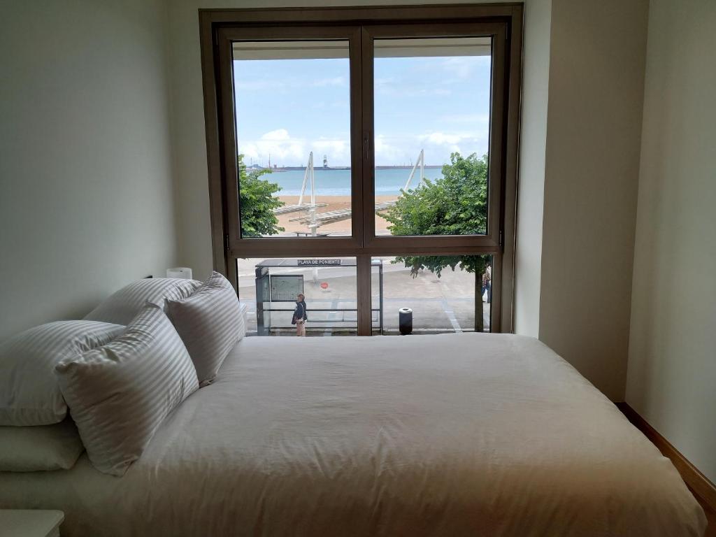 Schlafzimmer mit einem großen Fenster mit Blick auf den Strand in der Unterkunft Apto. Vista Playa Poniente in Gijón
