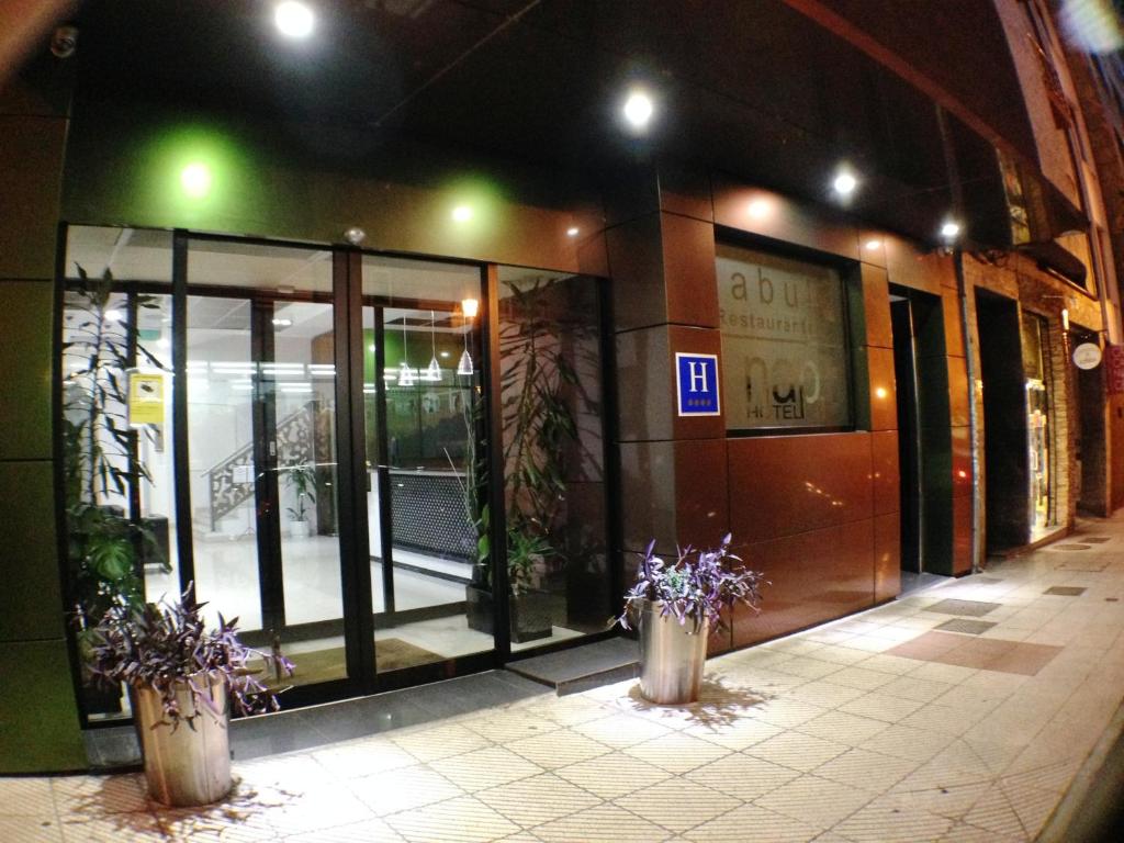 an entrance to a building with glass doors and purple flowers at Nap Oviedo in Oviedo