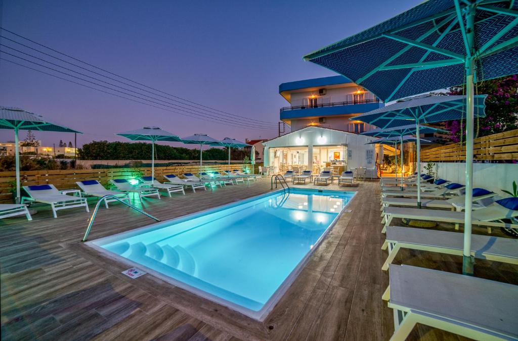 basen z leżakami i parasolami obok budynku w obiekcie Emi Seaside w miejscowości Amoudara