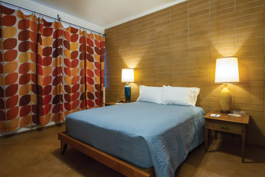 a bedroom with a bed and two lamps and a curtain at The Downtown Clifton Hotel in Tucson