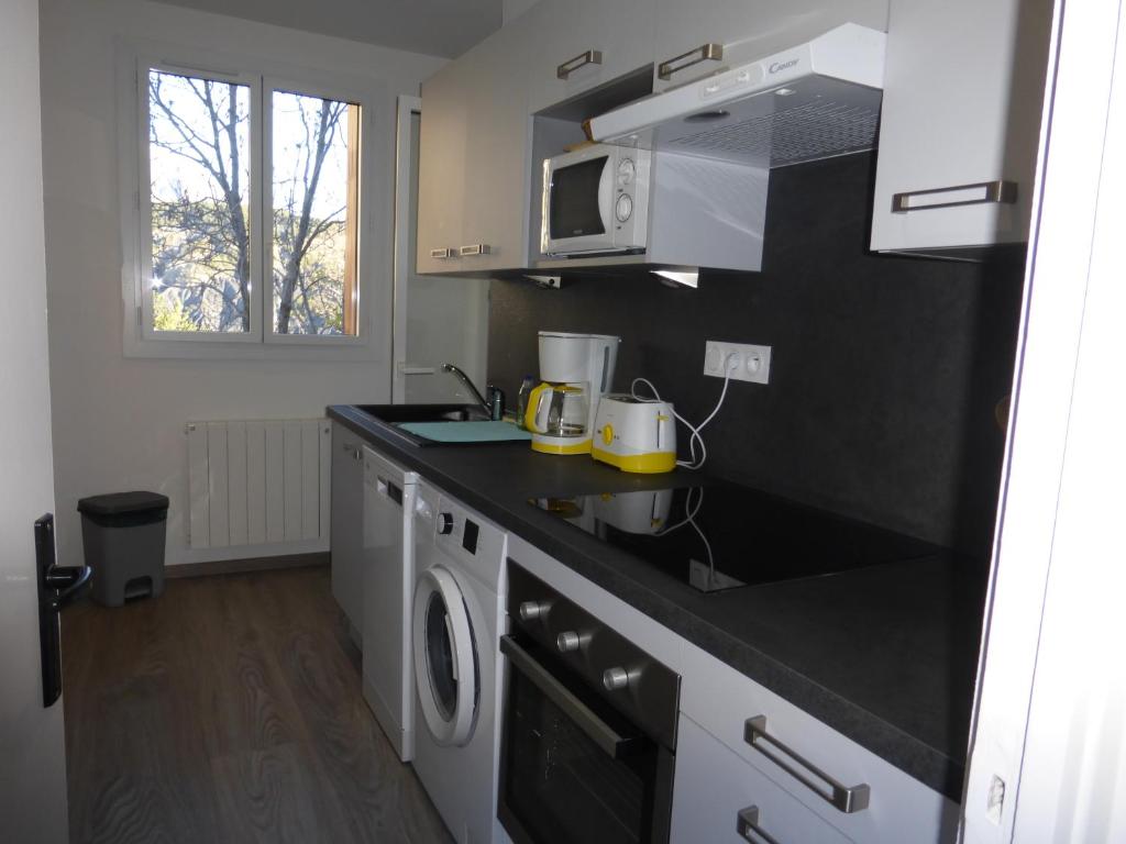 a kitchen with a black counter top and a microwave at RÉSIDENCE DES NEIGES 2052 in Le Sauze