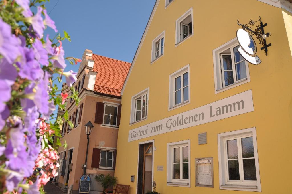 een geel gebouw met een bord waarop staat dat de kerk lamium in de tuin gebruikt bij Hotel Gasthof zum Goldenen Lamm in Harburg