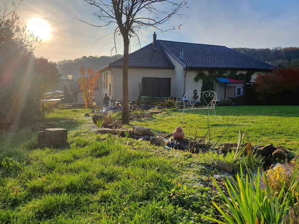 Una casa en un campo con el sol detrás. en Chez marie poppins, en Rozérieulles