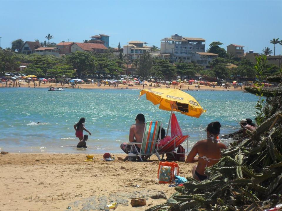 a group of people sitting on a beach with an umbrella at Pousada Brisas de Setiba in Guarapari