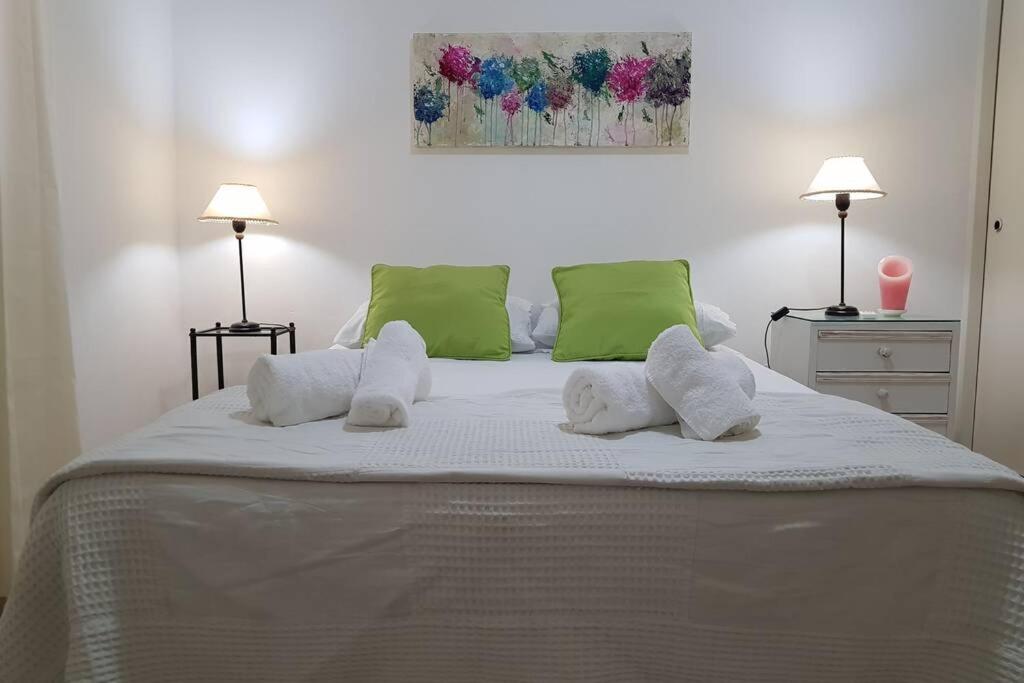 ein großes Bett mit weißen Kissen und grünen Kissen in der Unterkunft Alquiler Temporario Junin in Junín