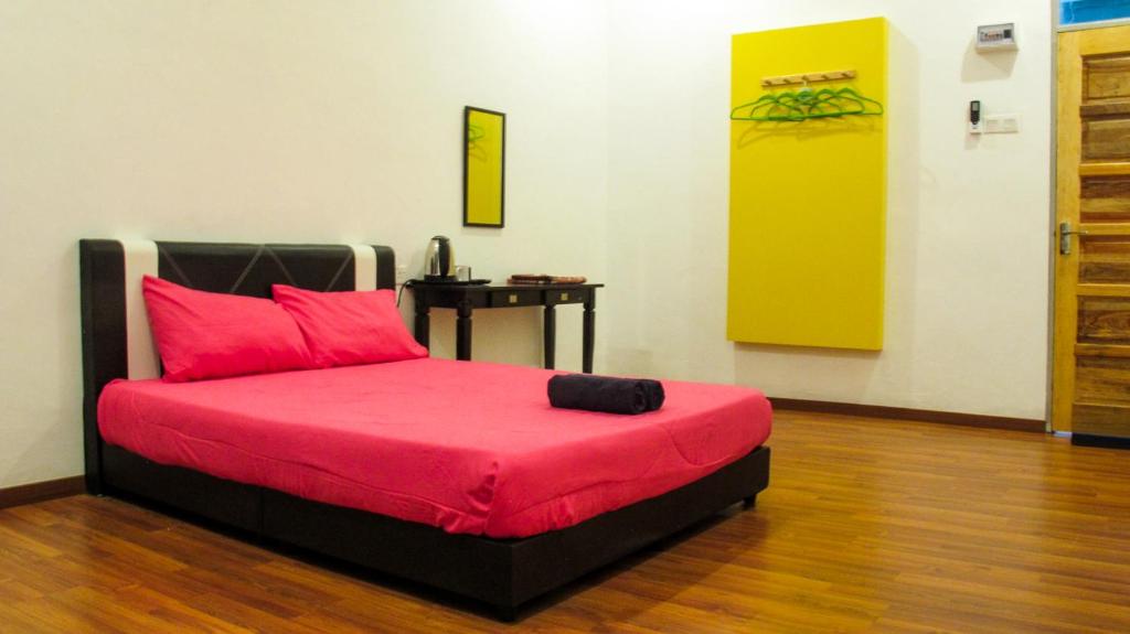 a bedroom with a bed with pink pillows and a table at Andalus beach residence in Marang