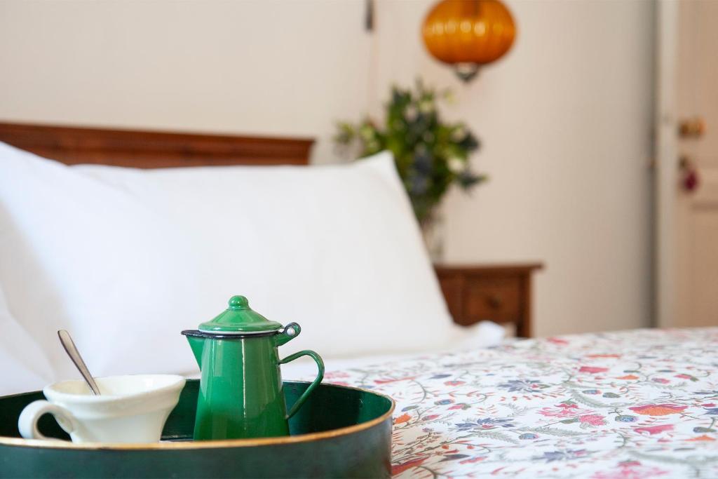 a green tea kettle and a cup on a bed at Le Stanze Di Santa Croce in Florence