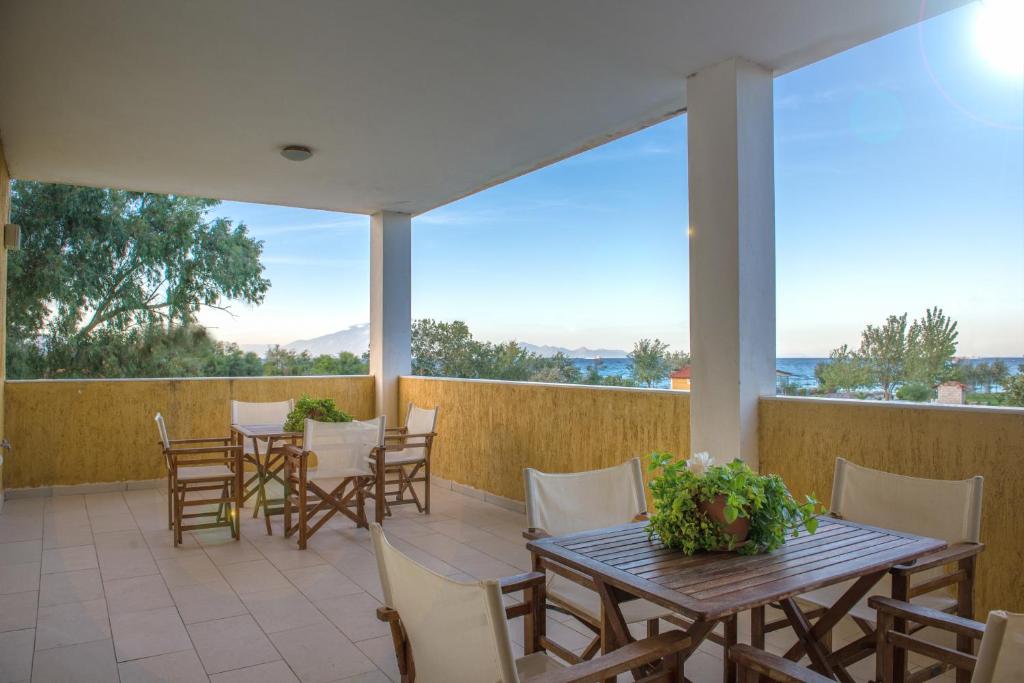 un patio con mesas y sillas en el balcón en Villa Pouliezos Apartments, en Alikanas