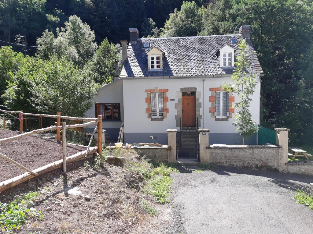 a small white house with a driveway in front of it at Maison 10 personnes Chez Perrine et Nicolas in La Bourboule