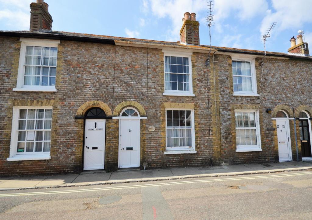 a brick building with white doors on a street at Admirals Cottage in Yarmouth