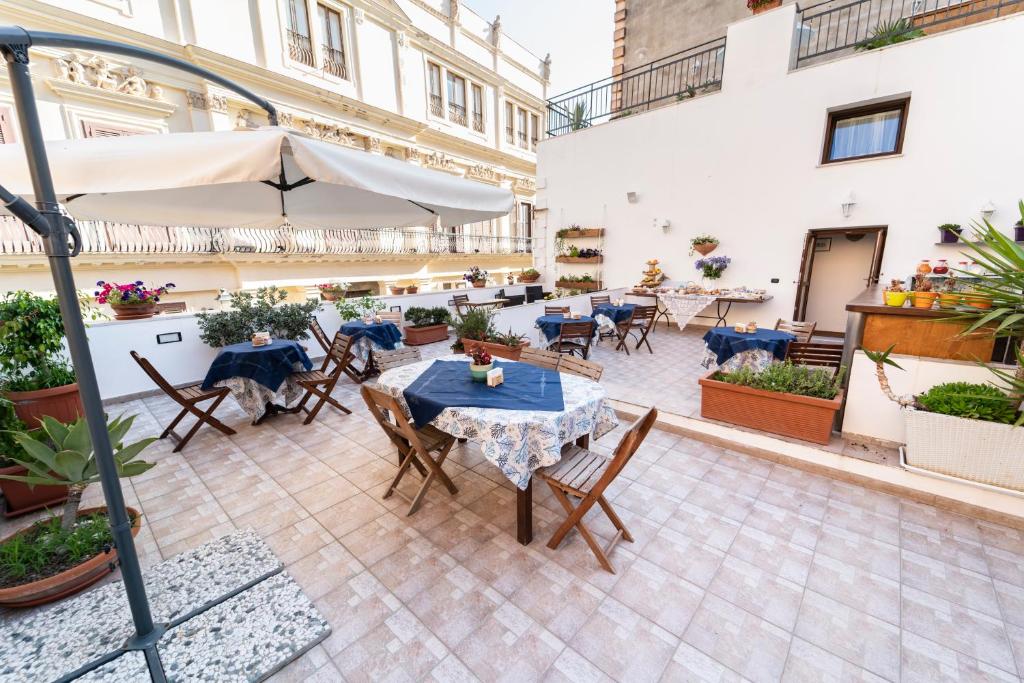 a patio with tables and chairs and an umbrella at Residence Garibaldi in Trapani