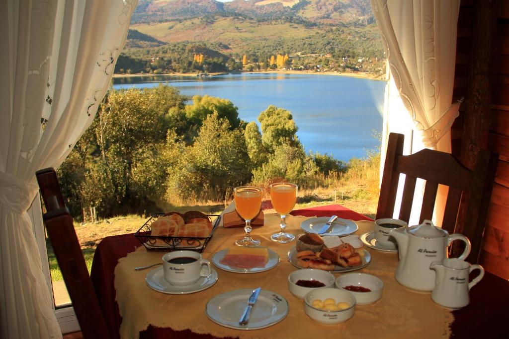 einen Tisch mit Speisen und Getränken und Seeblick in der Unterkunft Hosteria Al Paraiso in Villa Pehuenia