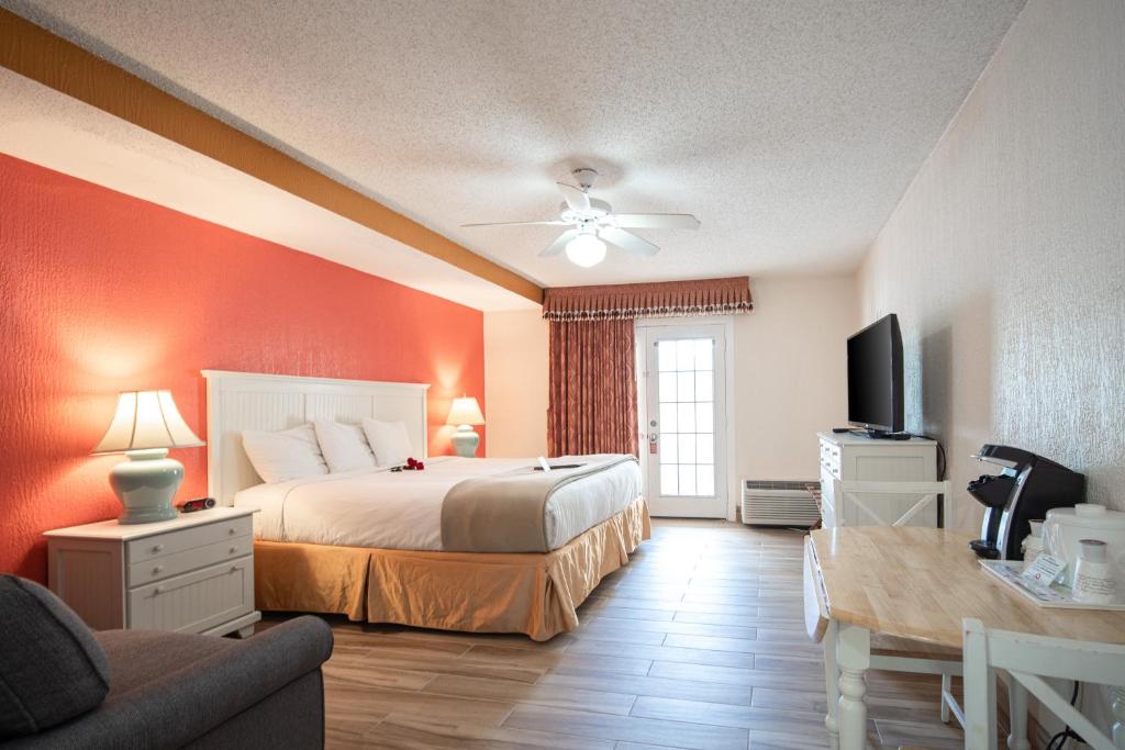 1 dormitorio con 1 cama, TV y sofá en Island Sun Inn & Suites - Venice, Florida Historic Downtown & Beach Getaway, en Venice