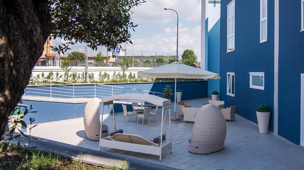 um pátio com uma mesa, cadeiras e um guarda-sol em Eracle Hotel em Volla