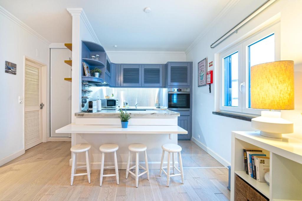 une cuisine avec des placards bleus et un comptoir avec des tabourets dans l'établissement JOIVY Superb Studio in Cascais Centre, à Cascais