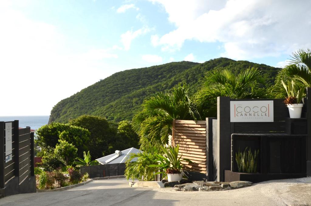 ein Schild für ein Hotel mit einem Berg im Hintergrund in der Unterkunft Villa Coco Cannelle in Deshaies