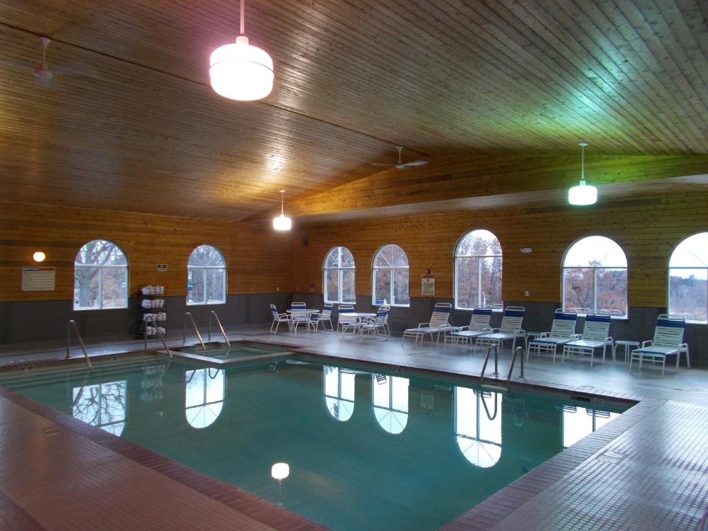 - une grande piscine dans un bâtiment avec des tables et des chaises dans l'établissement Northwoods Best Inn - Chetek, à Chetek