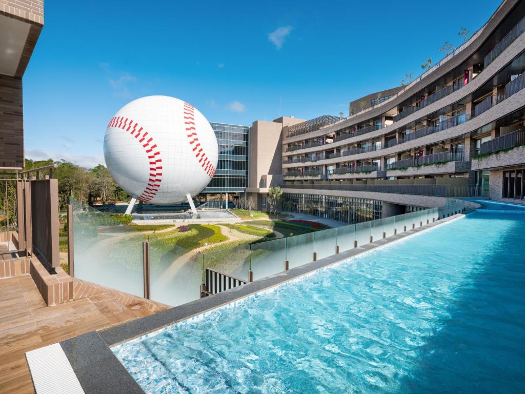 una pelota gigante de béisbol y una pelota delante de un edificio en Fame Hall Garden Hotel, en Longtan