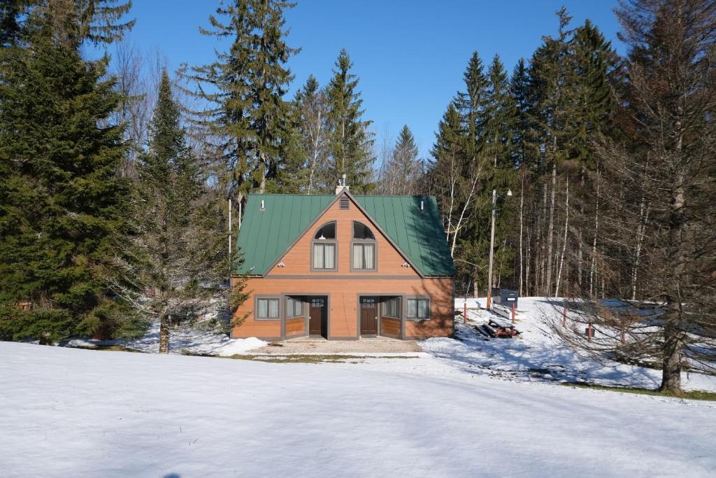 an orange house with a green roof in the snow at Ski in/out Spruce Glen Townhomes on Great Eastern Trail in Killington
