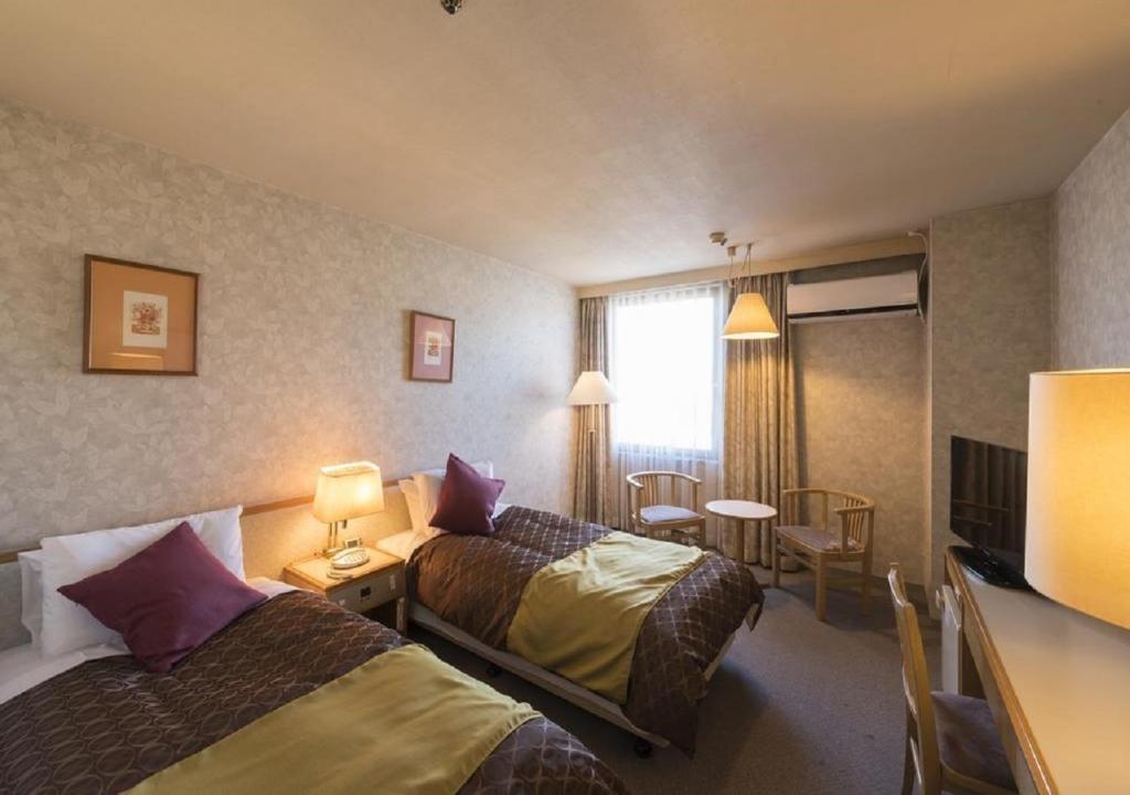Habitación de hotel con 2 camas y mesa en skyhotel uozu / Vacation STAY 59597, en Uozu